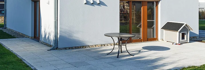 Gepflasterte Terrasse mit Tisch und Hundehütte